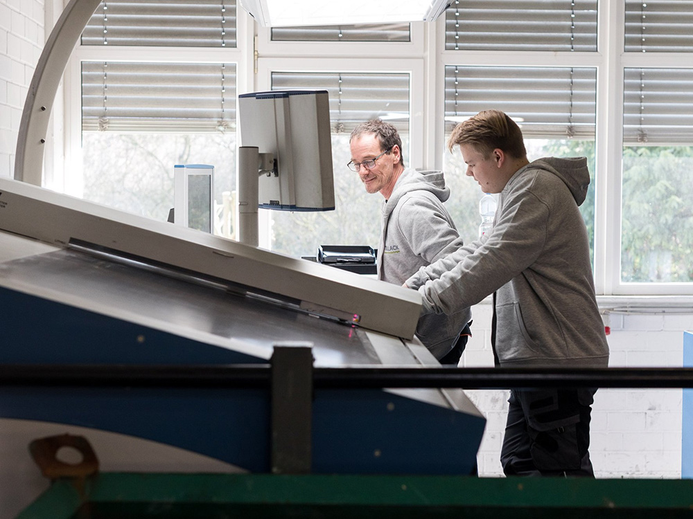 Mitarbeiter in der Verpackungsproduktion bei Tillack Creativ Verpackungen Zwei Mitarbeiter bedienen eine Produktionsmaschine in der Verpackungsfertigung von Tillack Creativ Verpackungen